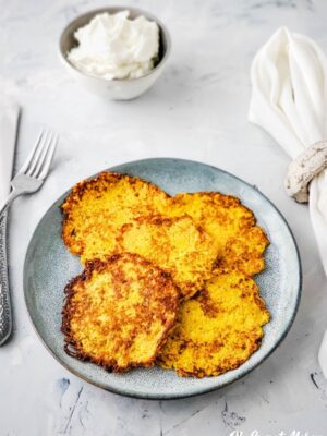 Plate of cooked latkes with bowl of sour cream