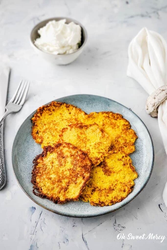 Plate of cooked latkes with bowl of sour cream