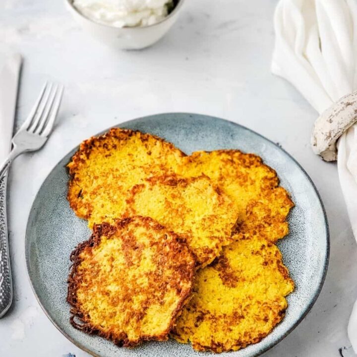 Plate of cooked latkes with bowl of sour cream