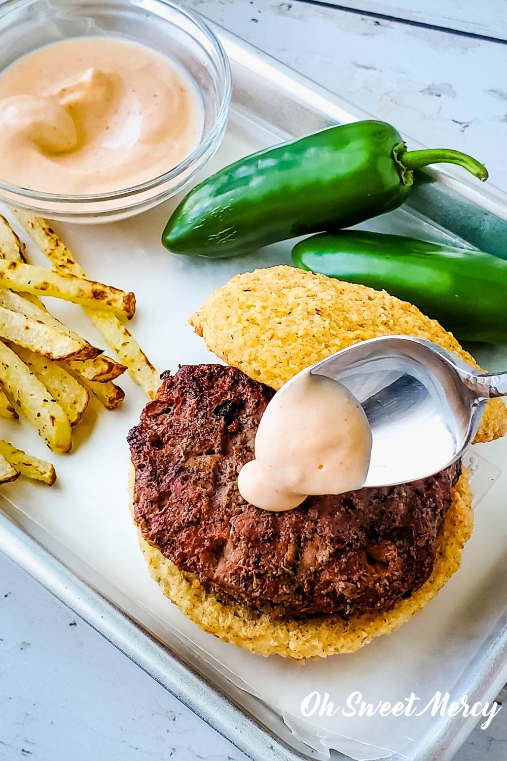 spooning Sriracha burger sauce onto jalapeno burger