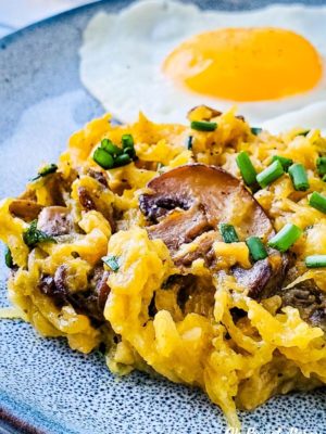 Buttery Garlic Mushroom and Chive Spaghetti Squash on a plate with a fried egg