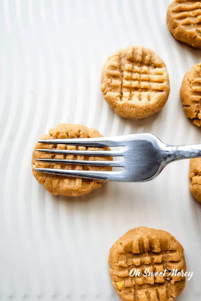 Making criss cross pattern with a fork on Easy No Bake Peanut Butter Cookies.