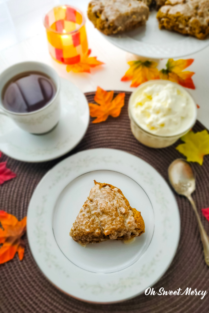 Plain glazed pumpkin scone on a plate with tea and clotted cream