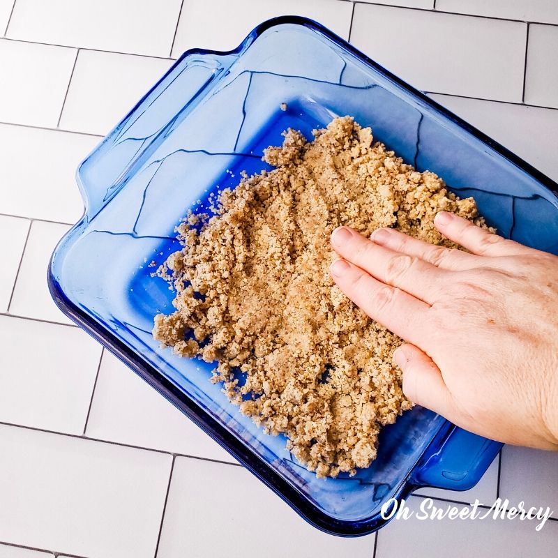 Patting crust mixture into baking dish