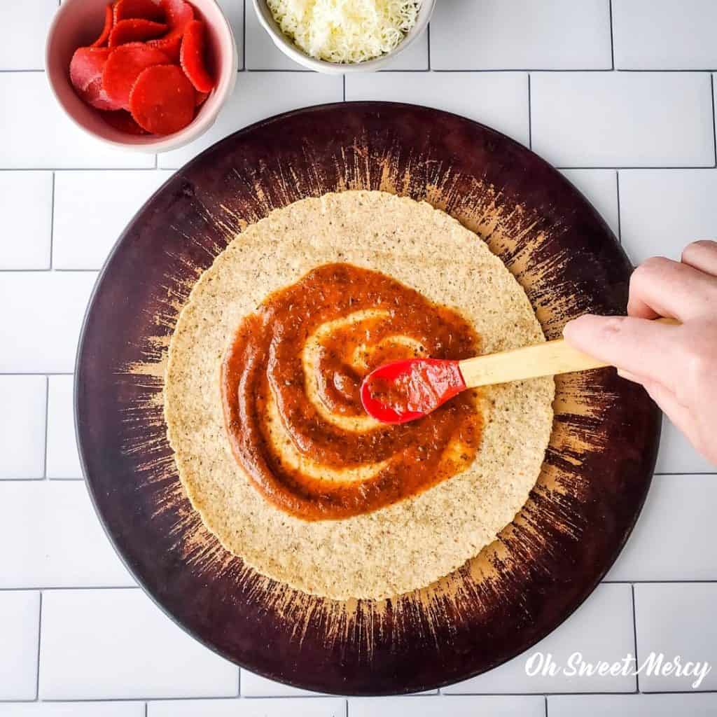 spreading pizza sauce on low carb tortilla 