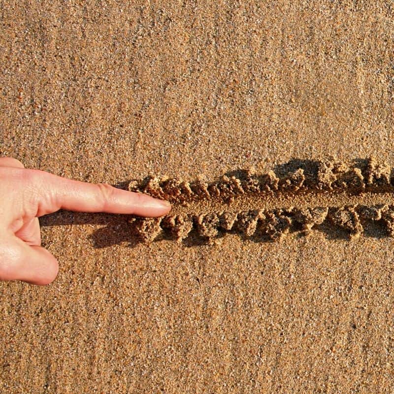 Finger drawing line in sand