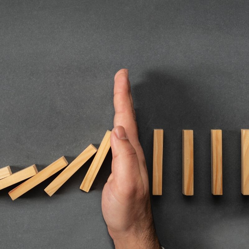 hand stopping falling dominoes