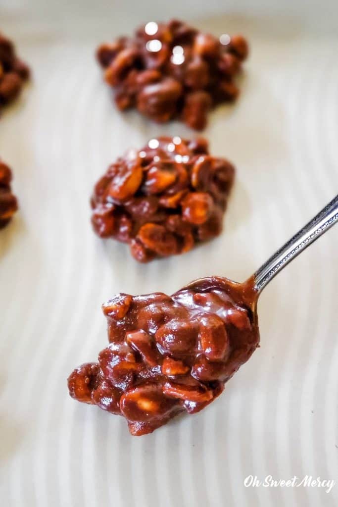 Dropping spoonfuls of acai chocolate nut clusters onto baking sheet