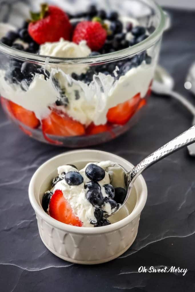 Spooning layered berry dessert into a bowl