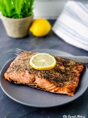 Lemon Dill Air Fryer Salmon on a gray plate with slice of lemon on top.