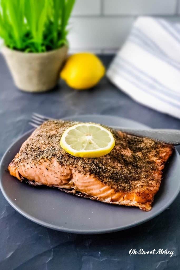 Lemon Dill Air Fryer Salmon on a gray plate with slice of lemon on top.