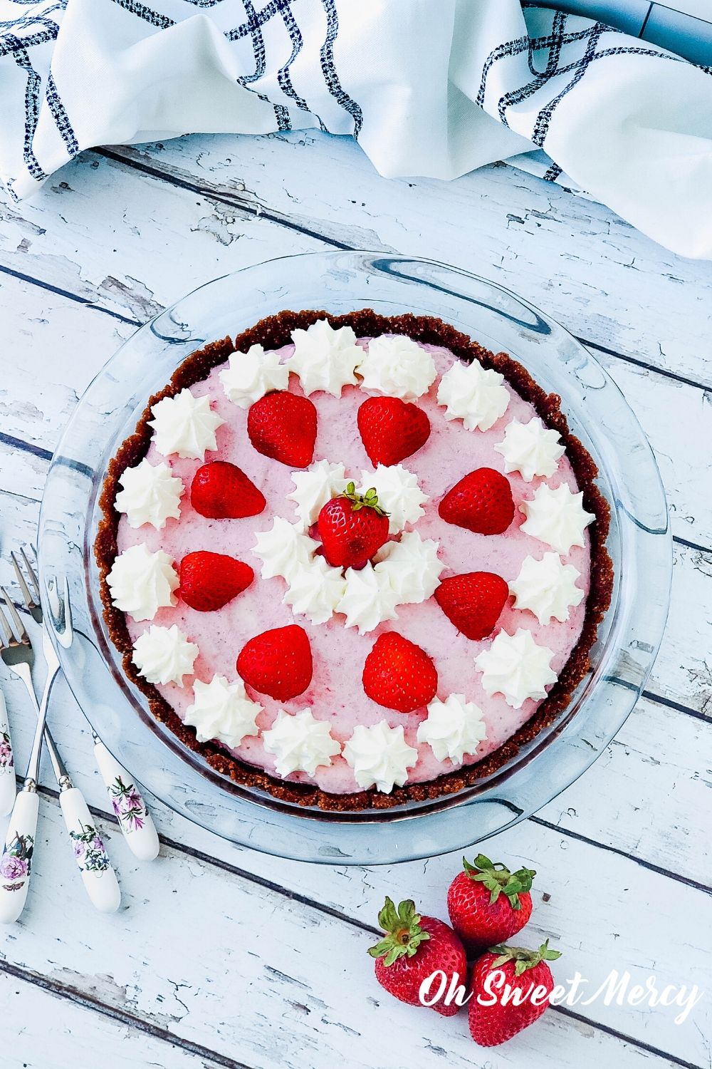 Whole low carb strawberry freezer pie decorated with dollops of whipped cream and strawberry halves