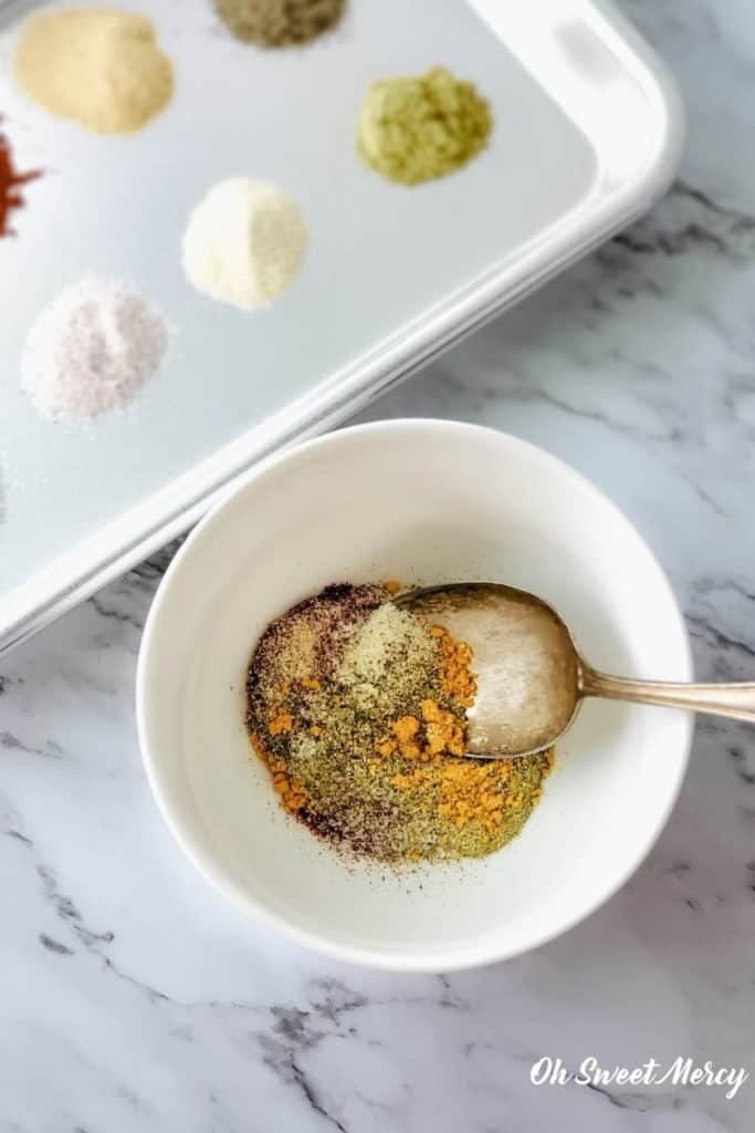 Mixing bulk breakfast sausage seasoning ingredients in a bowl.