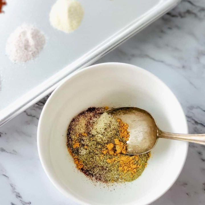 Mixing bulk breakfast sausage seasoning ingredients in a bowl.