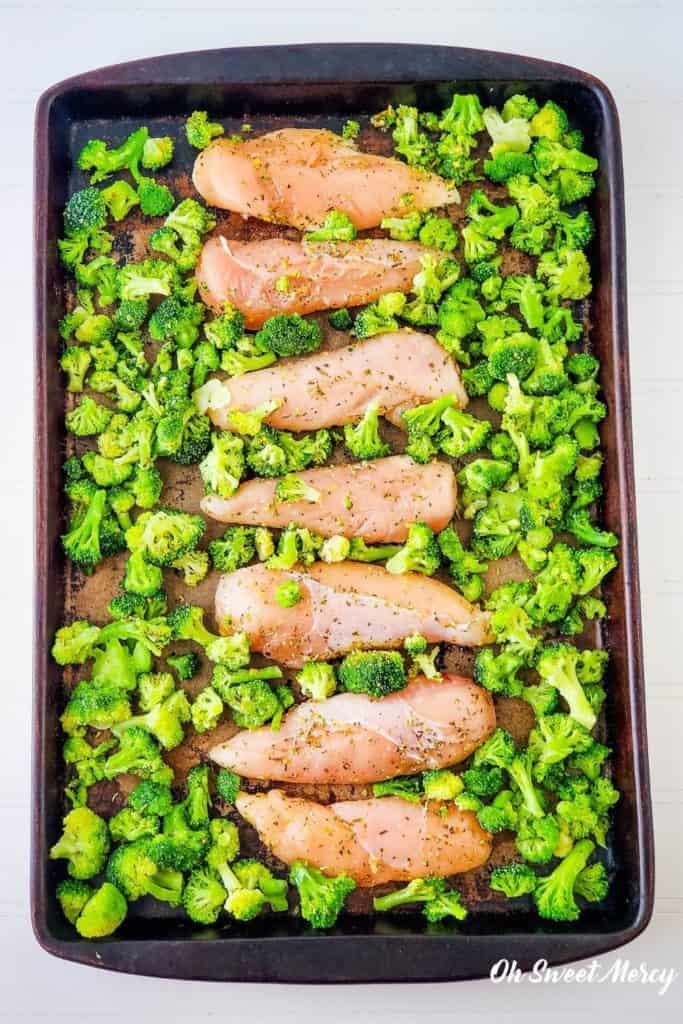 Seasoned chicken and broccoli on baking sheet