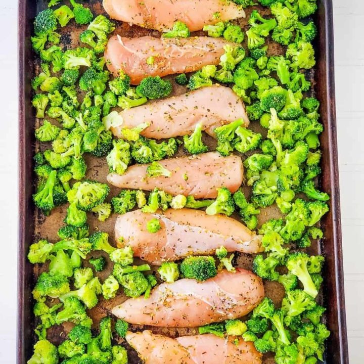 Seasoned chicken and broccoli on baking sheet