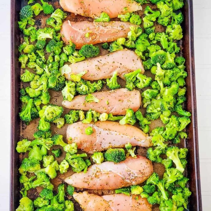 Seasoned chicken and broccoli on baking sheet