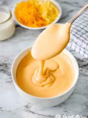 Spooning thick, creamy, easy low carb cheese sauce into a bowl.