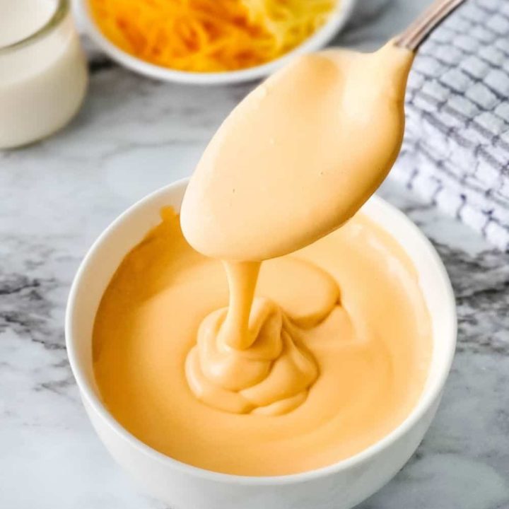 Spooning thick, creamy, easy low carb cheese sauce into a bowl.