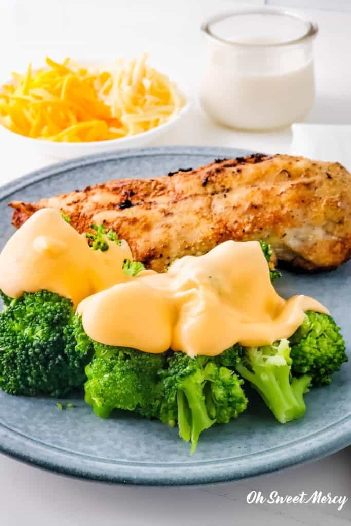 Broccoli with cheese sauce on a plate with chicken breast.