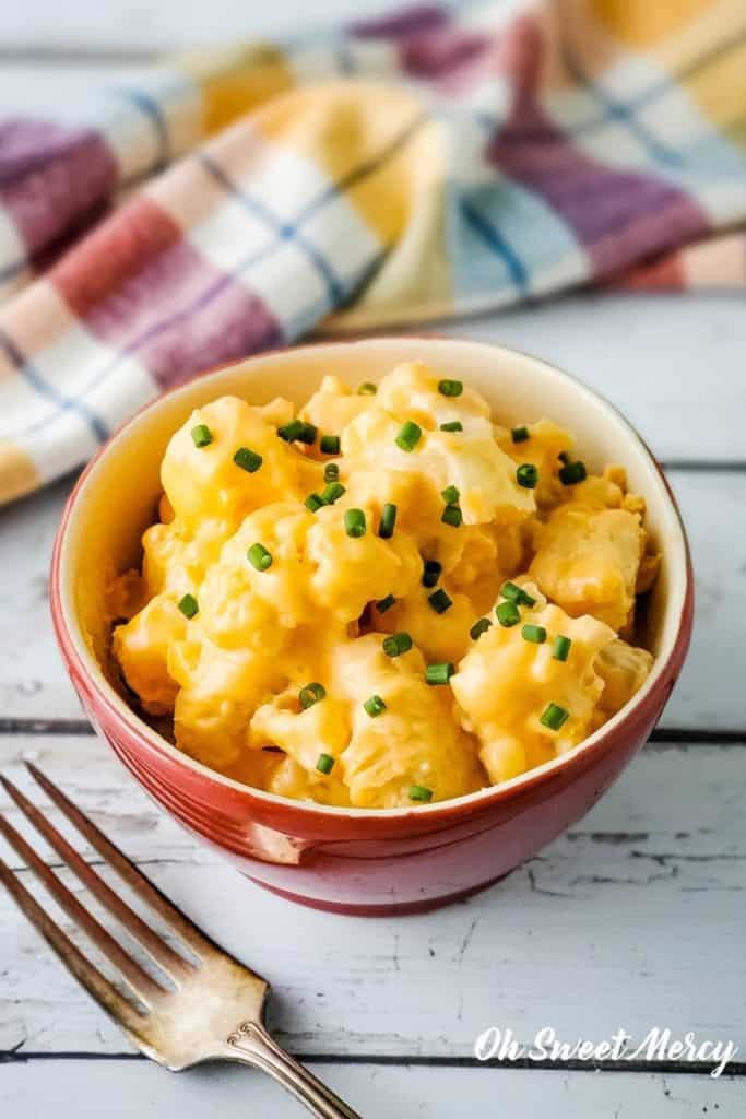 Bowl of low carb cheesy cauliflower with fresh chives