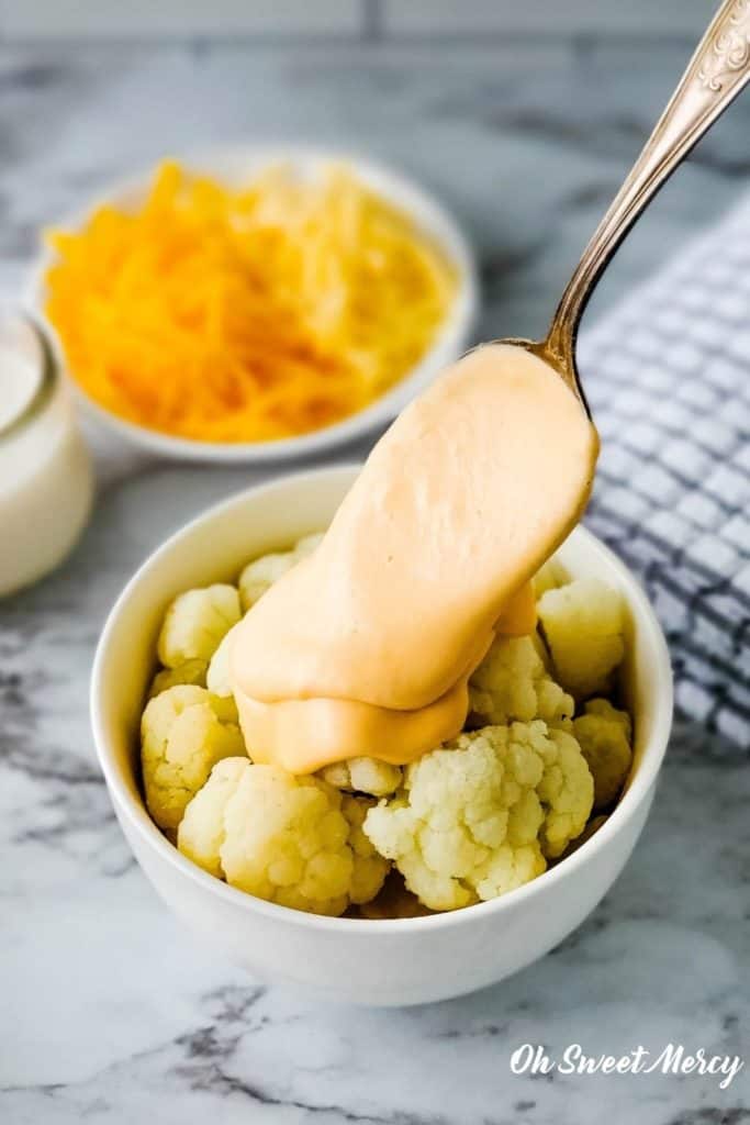 Spooning cheese sauce over cauliflower