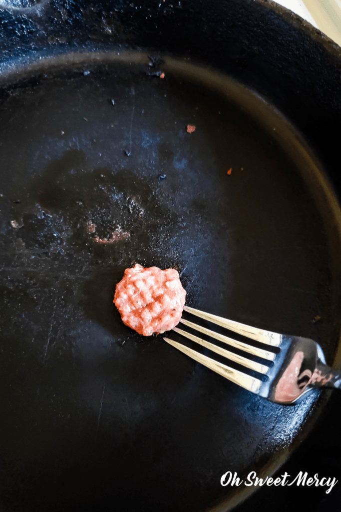 Testing a small portion of sausage mixture for seasoning by cooking a bite size piece in a skillet