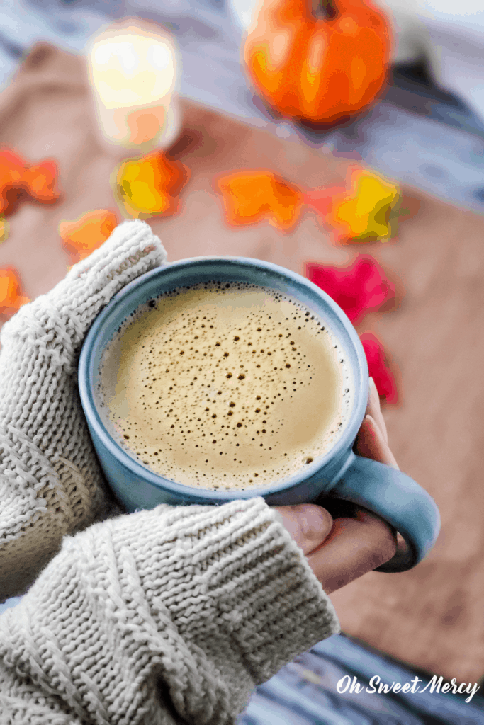 Cozy sweater around hands holding a mug of warm, creamy pumpkin spice steamer