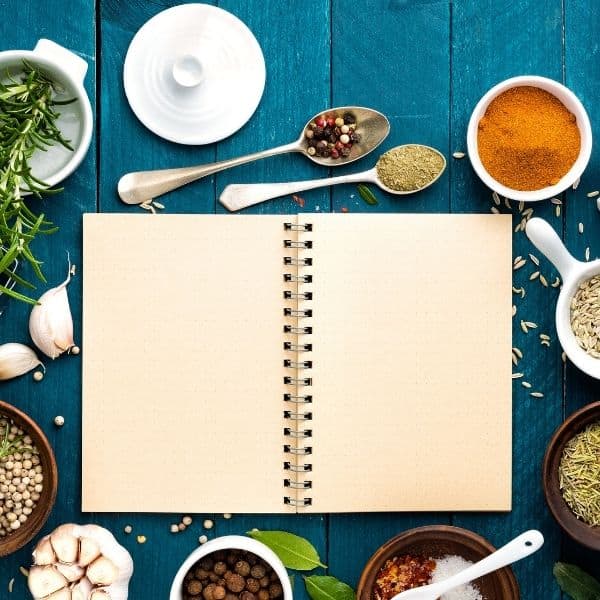 blank notebook surrounded by spices on blue background