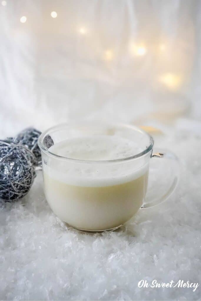Clear glass mug of frothy dairy free creamy peppermint white hot chocolate
