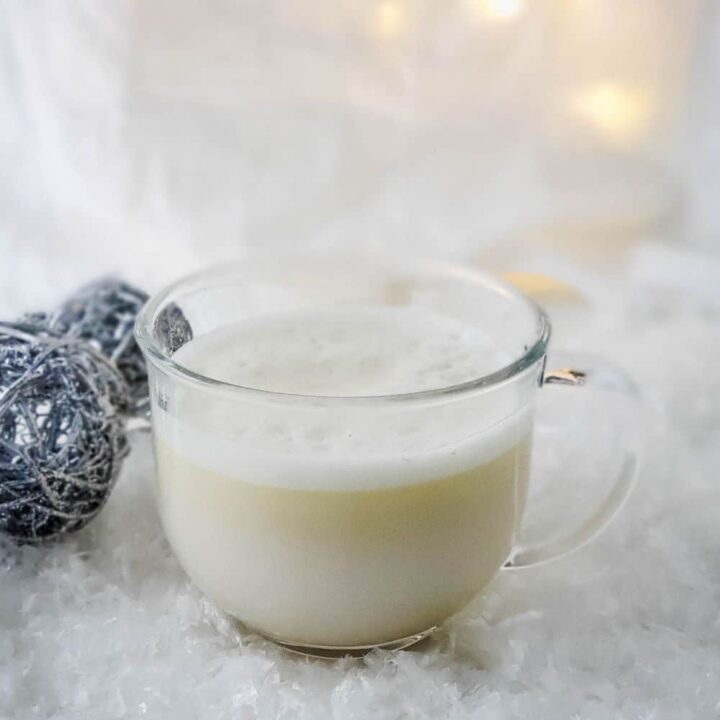 Clear glass mug of frothy dairy free creamy peppermint white hot chocolate