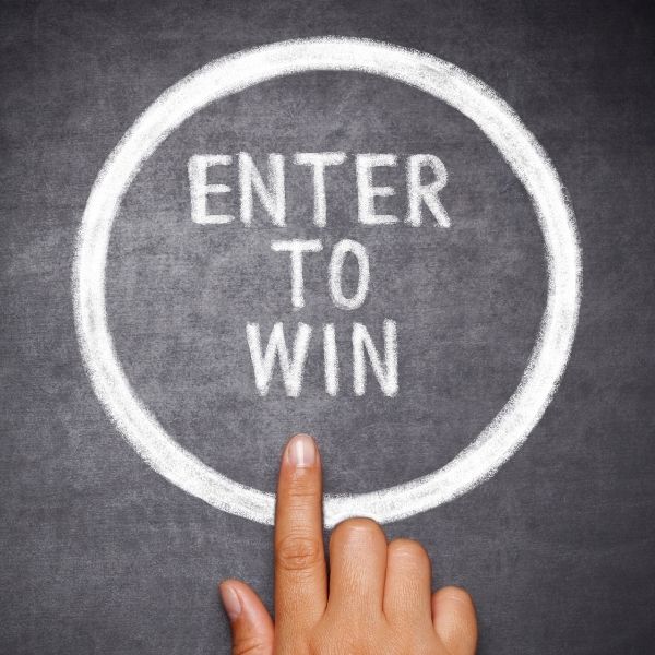 finger pointing at "enter to win" written on chalkboard