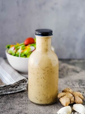 Bottle of Asian Sweet and Tangy Salad Dressing with bowl of salad in the background