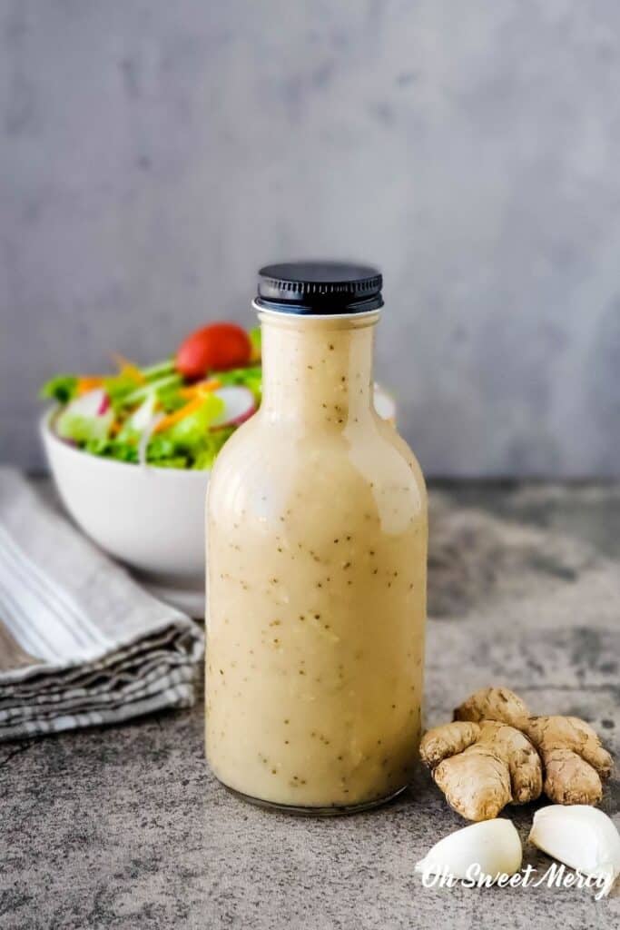 Bottle of Asian Sweet and Tangy Salad Dressing with bowl of salad in the background