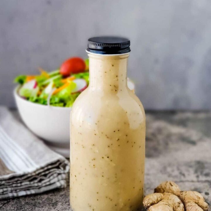 Bottle of Asian Sweet and Tangy Salad Dressing with bowl of salad in the background