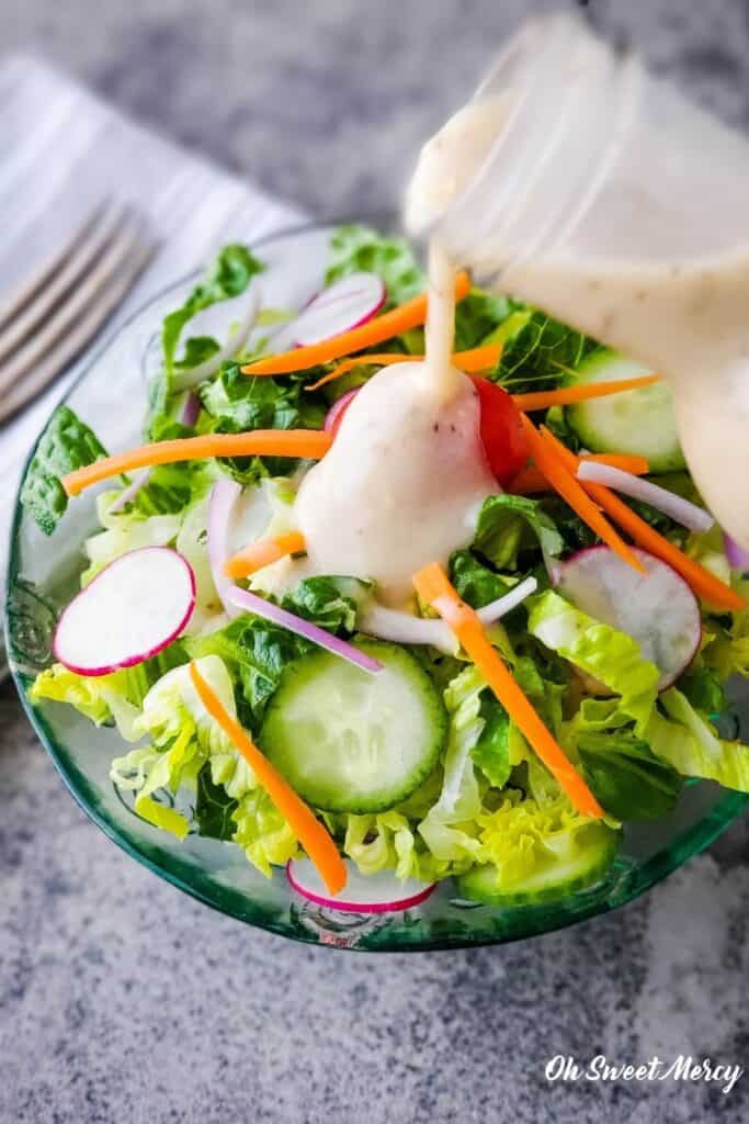 Pouring dressing over a bowl of salad