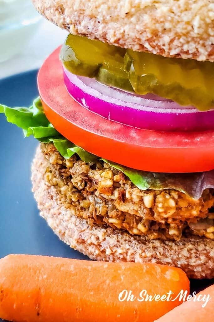 Close up of lentil burger on bun with lettuce, tomato, onion, pickles