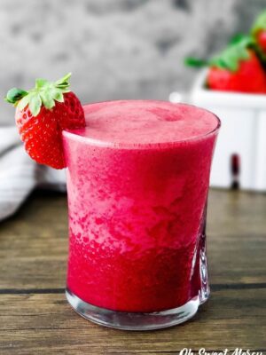 Glass of strawberry beet smoothie with strawberry on the rim