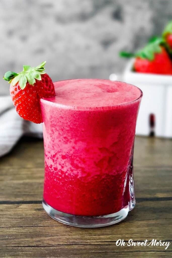 Glass of strawberry beet smoothie with strawberry on the rim