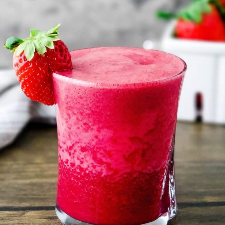 Glass of strawberry beet smoothie with strawberry on the rim