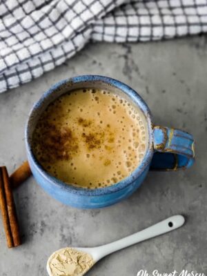 Overhead shot of moon milk in blue mug with white ceramic spoon containing ashwagandha powder