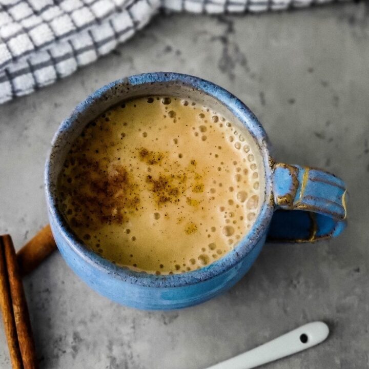 Overhead shot of moon milk in blue mug with white ceramic spoon containing ashwagandha powder