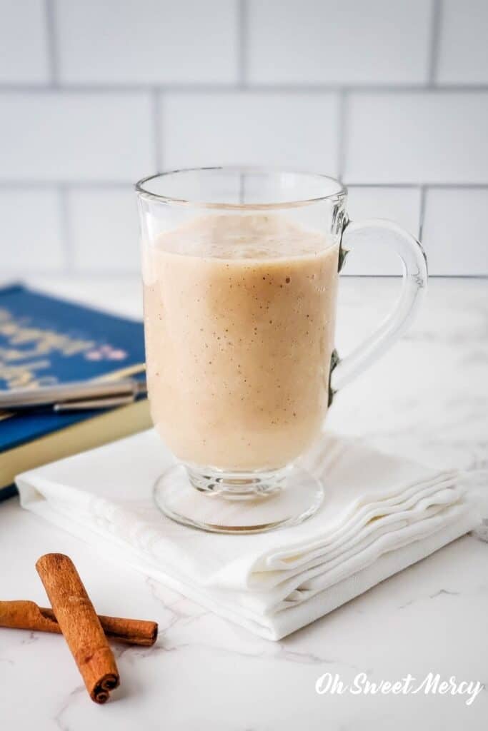 Clear glass mug of moon milk on a folded napkin with book in background