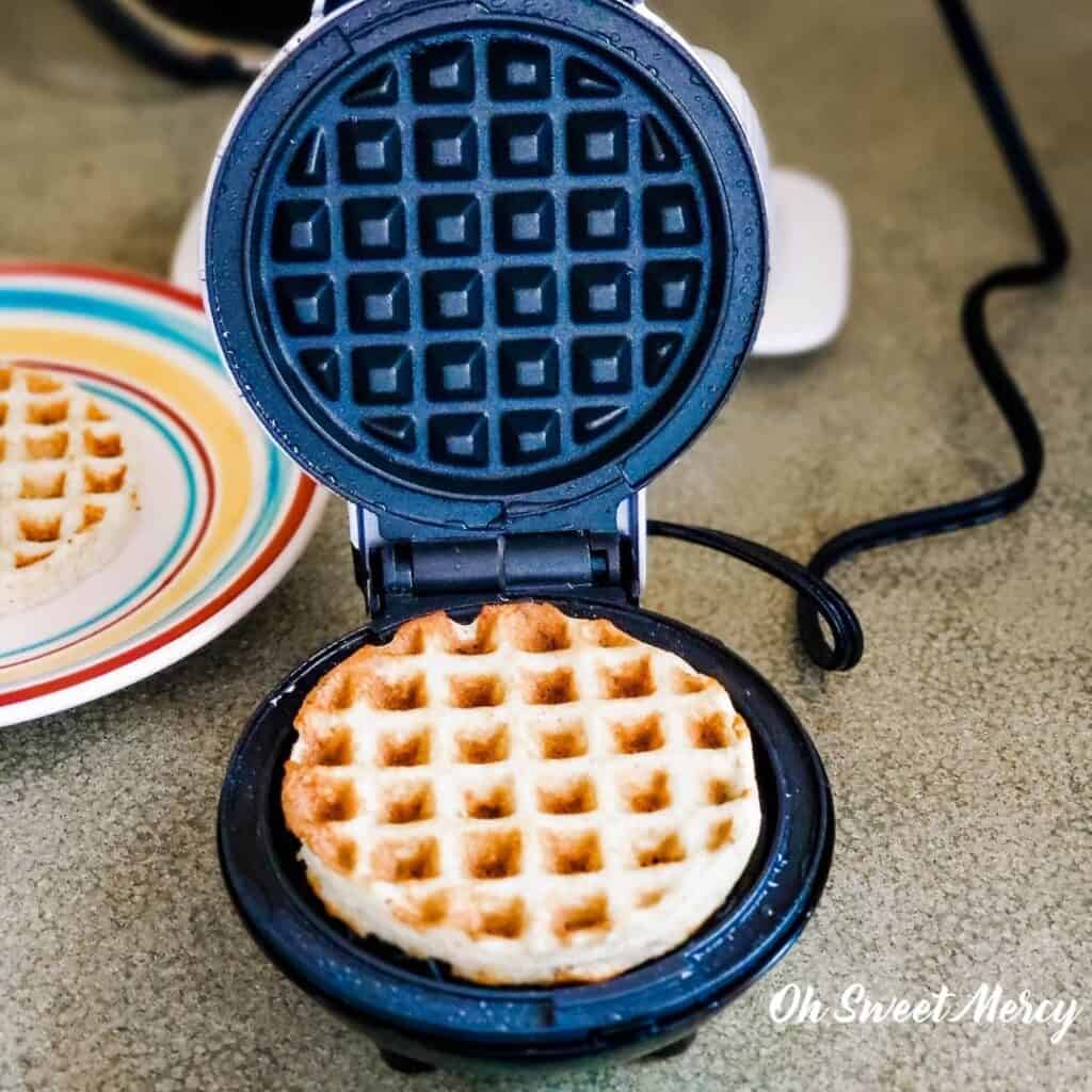 Cooked mini waffle in the waffle maker with lid open