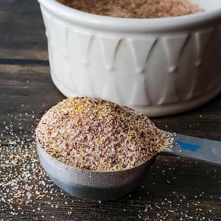 Heaping teaspoon of seasoning blend in front of white bowl.