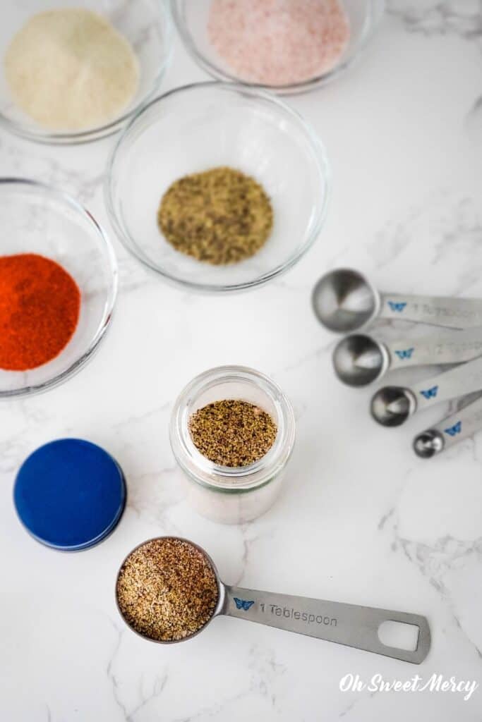 some of the spices in this seasoning blend in bowls with measuring spoons