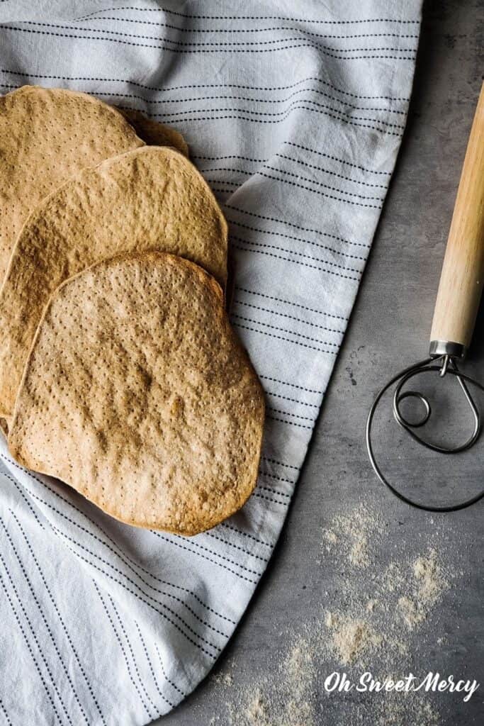 Sprouted wheat matzah on towel with dough whisk nearby