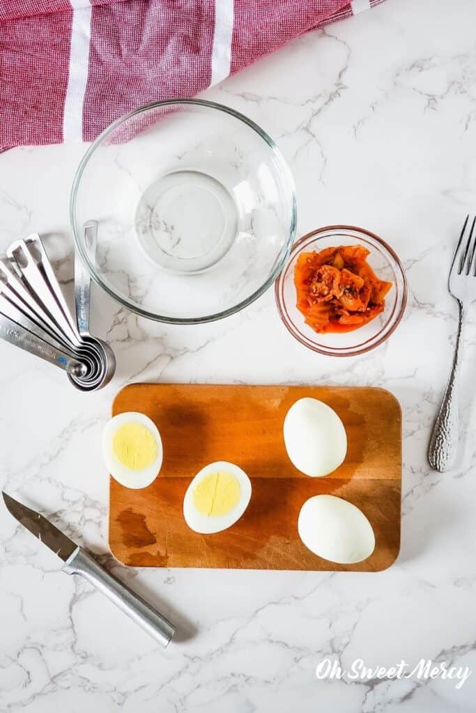 Preparing to make this recipe: cut hard cooked egg, bowl of kimchi, empty mixing bowl, measuring spoons