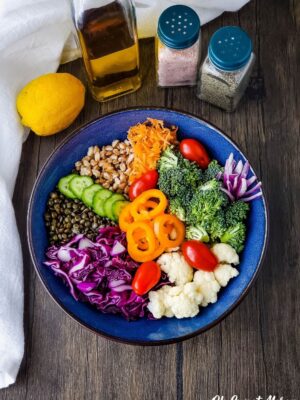 Bowl with grain bowl ingredients, lemon, olive oil, salt and pepper