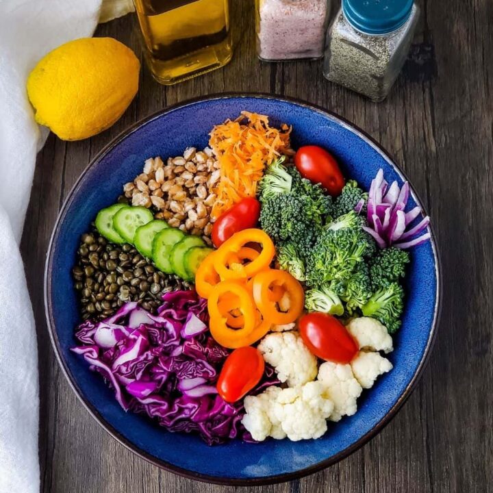 Bowl with grain bowl ingredients, lemon, olive oil, salt and pepper